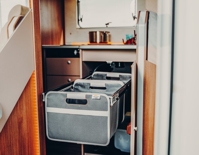 Pull-out fabric basket in the lower cabinet of the Carado motorhome kitchen