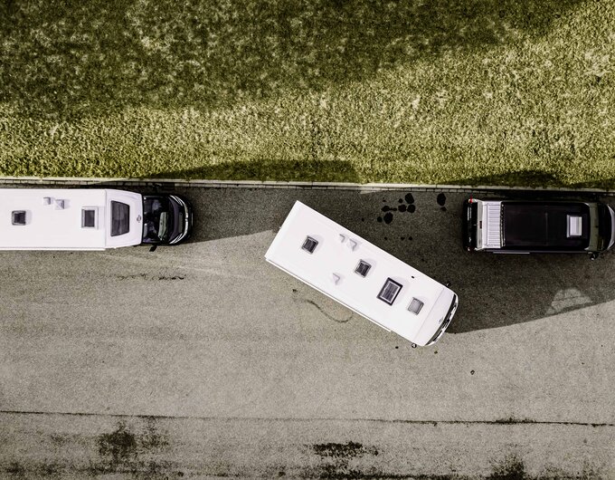 Drone view of two Carado motorhomes parking on asphalt beside a black camper van