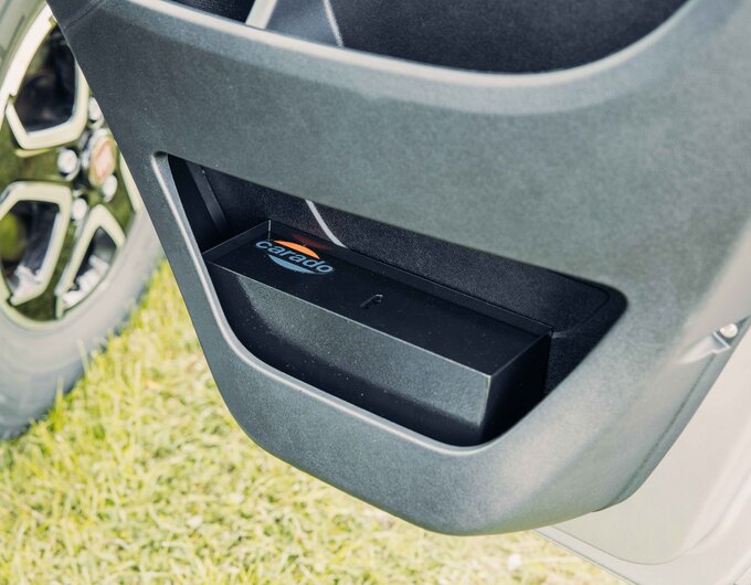 Storage compartment in the door of a Carado motorhome, close-up with a wheel in the background