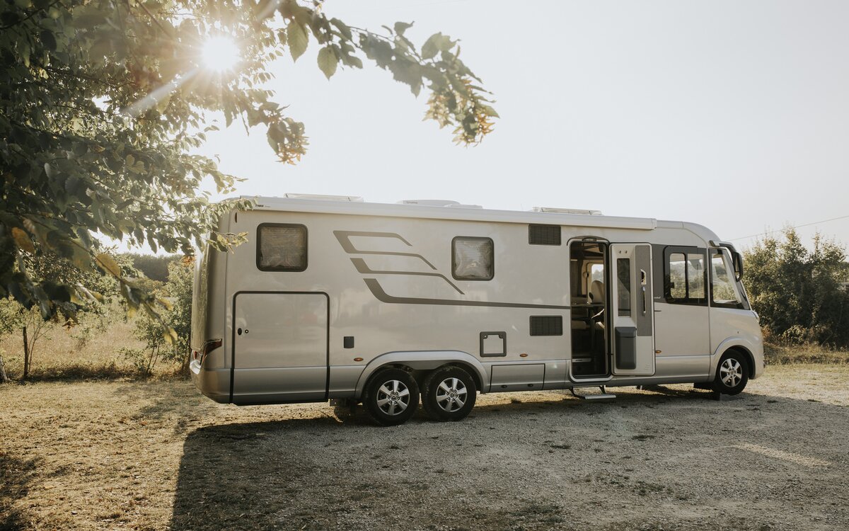 HYMER B-Klasse MasterLine I geparkeerd aan de rand van een weiland met de motorkap open als dubbelassig voertuig in een warm lichttafereel.