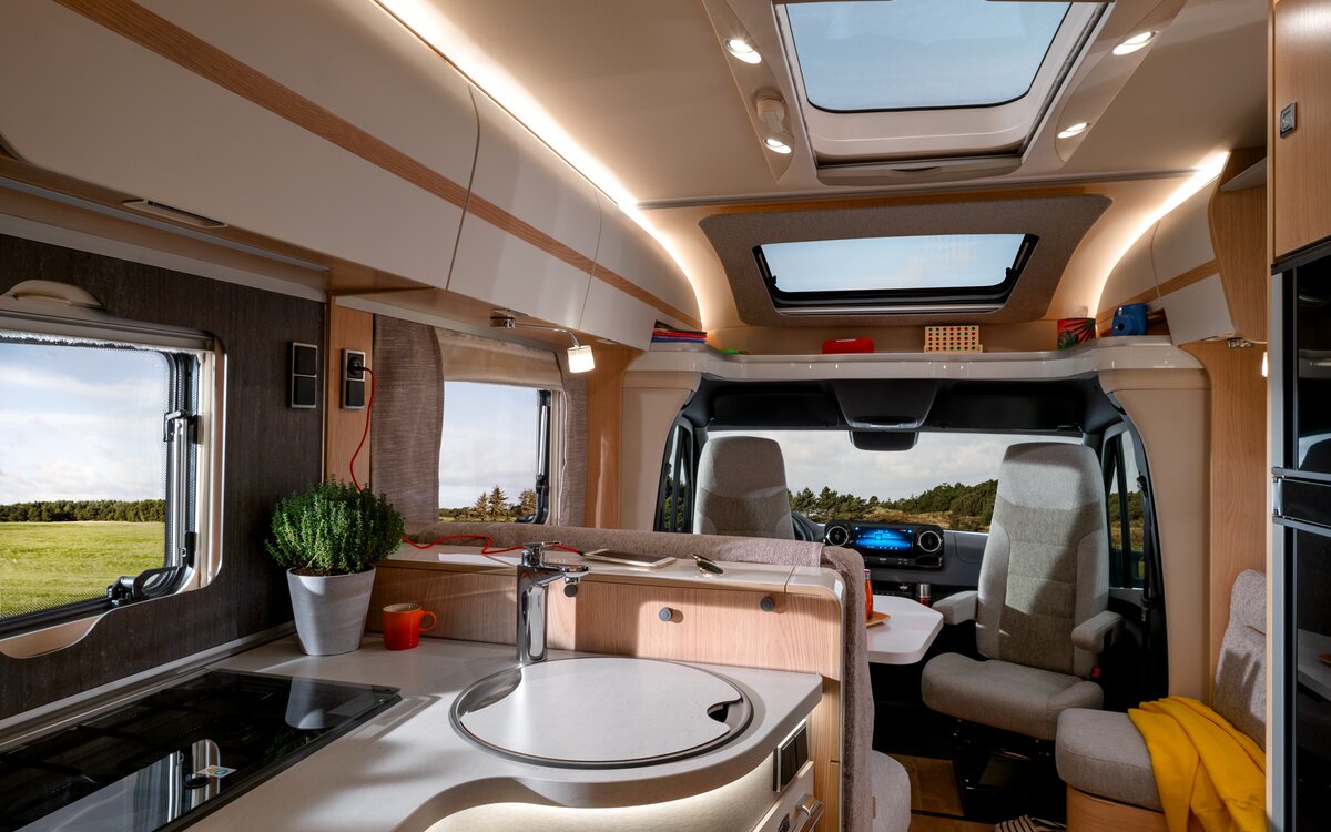 Opbergplank gevuld met speelgoed en opbergkasten boven de bestuurdersstoelen en het dakraam in de HYMER MasterLine T
