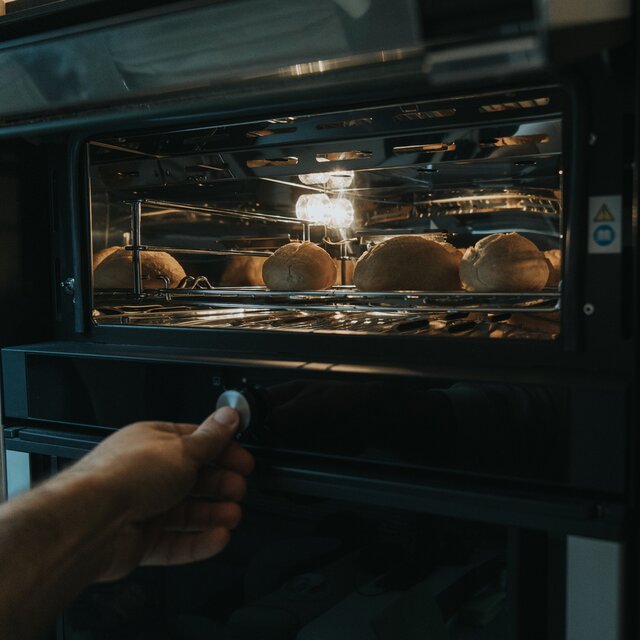 Bediening van de draaiknop van een oven in een camper waarin broodjes worden gebakken