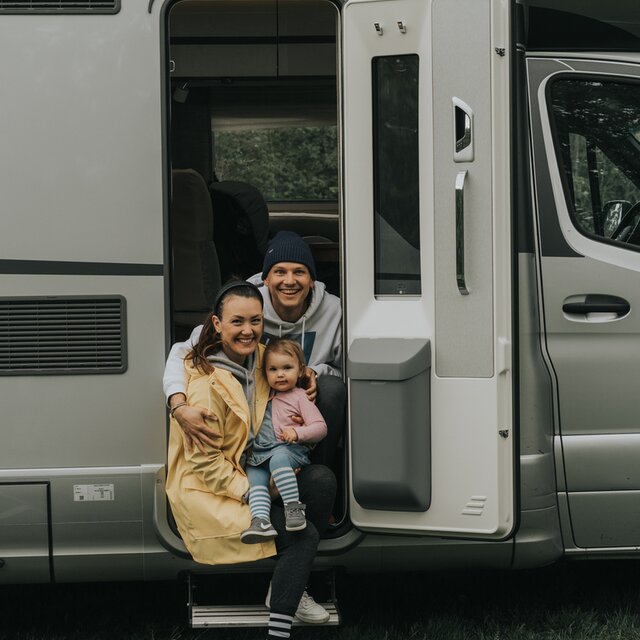 Jong paar dat met baby in de open carrosseriedeur van een camper zit