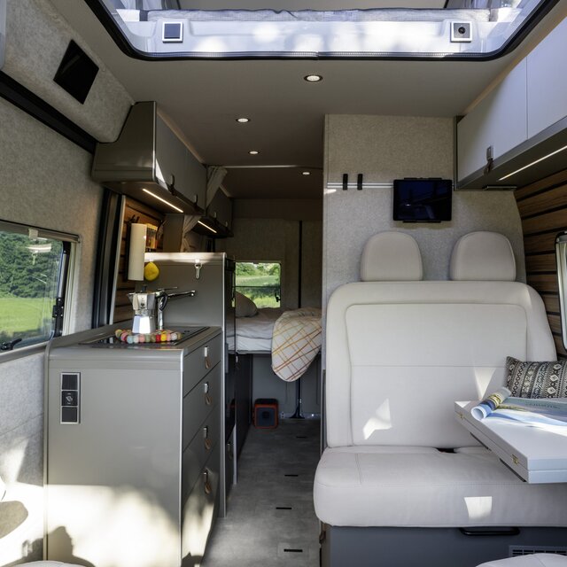 Wohnraum im HYMER Camper Van: Fahrersitze, Tisch, Sitzbank, Küche, Seitenwandfenster, Dachstauschränke, Hecktüre mit Fenster