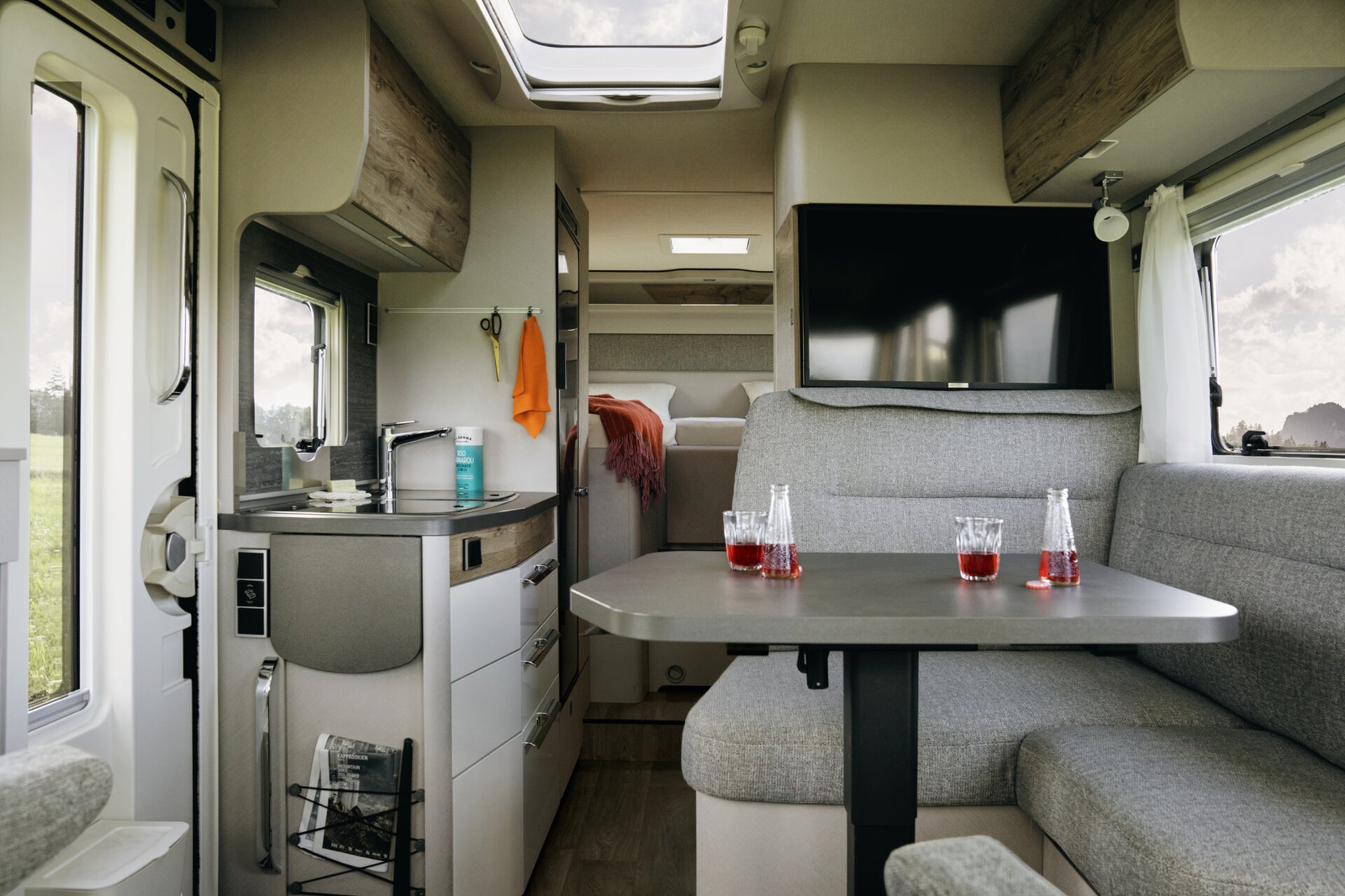 Interior of the HYMER Exsis 580 Pure: seating area, flat screen TV, entrance door, kitchen block, sleeping area
