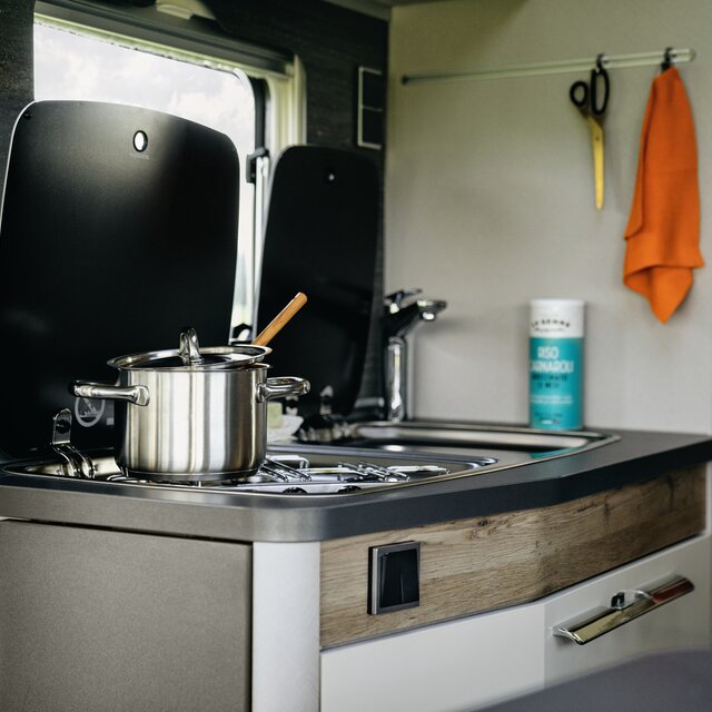 Kitchen block with a silver pot on the hob and other utensils in the Hymermobil Exsis-t 580 Pure
